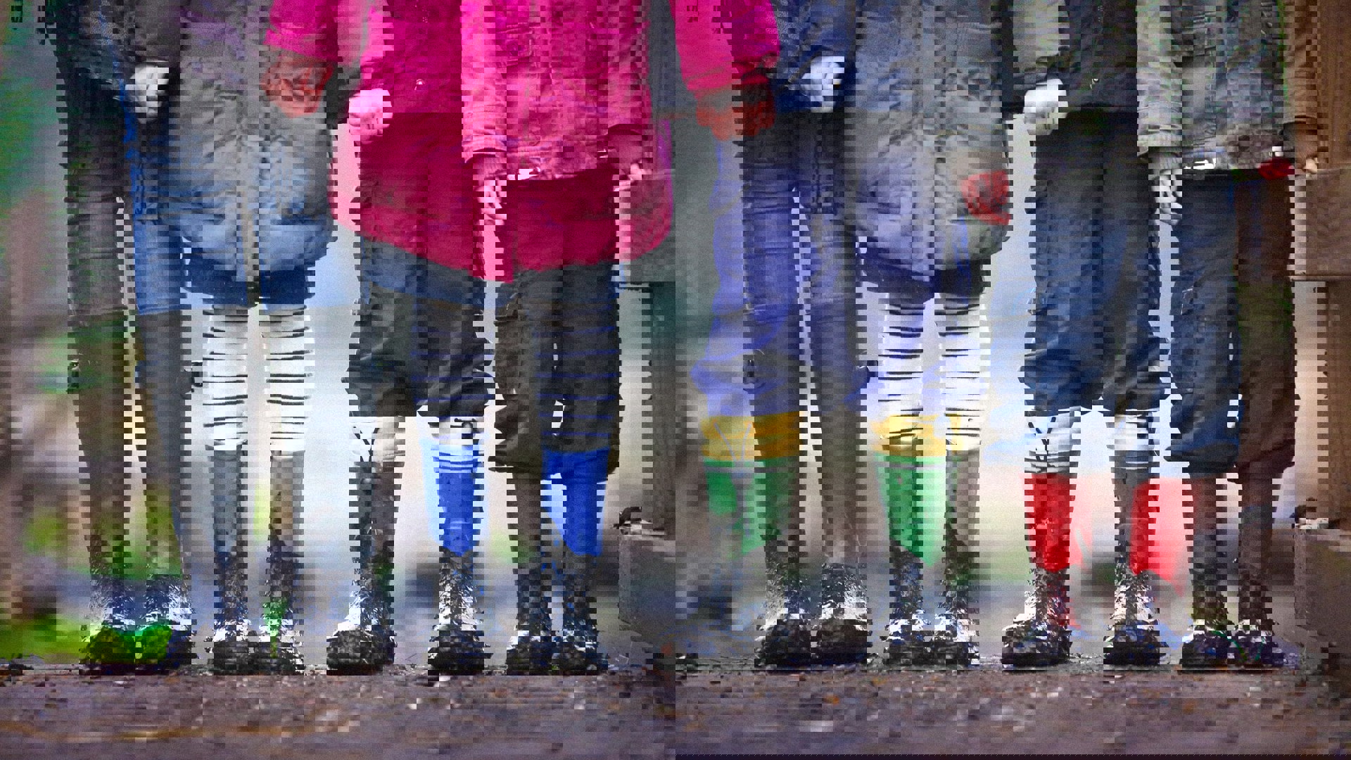 Fyra barn står bredvid varandra med gummistövlar utomhus