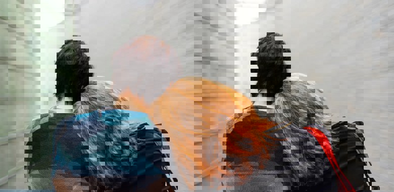 Två personer står varav den ena lutar huvudet på den andres axel