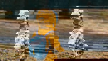 Barn med gul jacka och ryggsäck är ute och går 