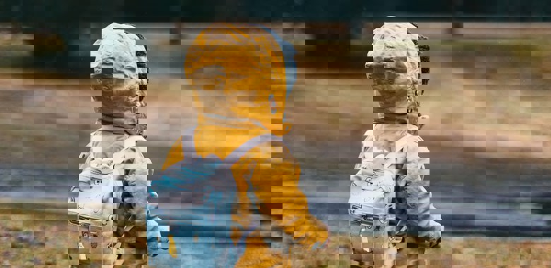 Barn med gul jacka och ryggsäck är ute och går 